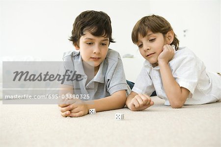 Deux garçons, allongé sur le sol en regardant vers le bas une paire de dés