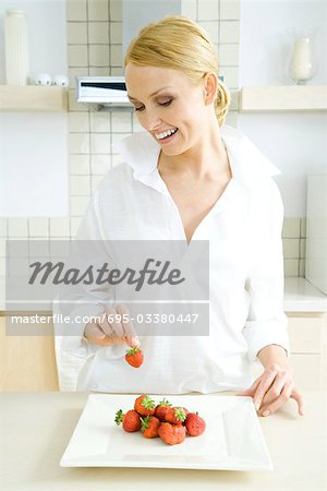 Femme prépare l'assiette de fraises fraîches