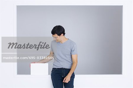 Man sitting on ledge, touching box, smiling