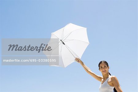 Femme brandissant parasol, souriant à la caméra