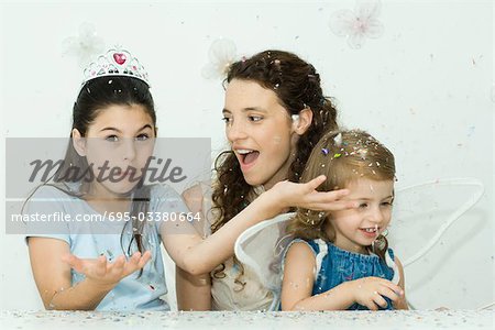 Girl throwing confetti, mother and sister watching