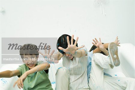 Mutter und zwei Söhne mit Partei-Zeichenfolge, besprüht wird lachen, die Hände erhoben