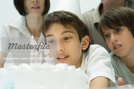 Boy making a wish before blowing out candles on birthday cake