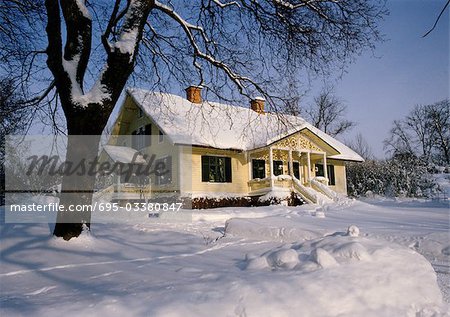 Suède, maison enneigée en milieu rural en plein jour, la neige qui recouvre le sol