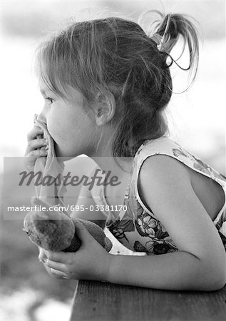 Girl holding stuffed animal in hand and piece of fabric over mouth, side view, b&w