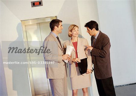 Zwei Geschäftsleute und geschäftsfrau steht vor dem Aufzug