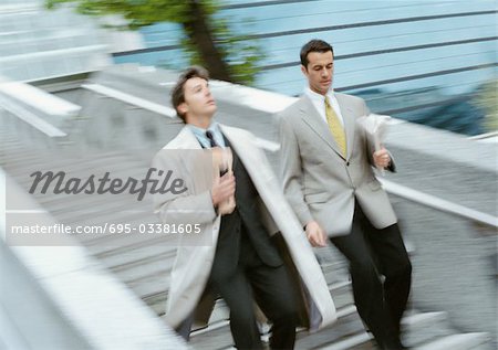 Two businessmen going down stairs side by side, blurred