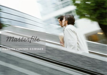 Two businessmen walking up stairs outside, blurred