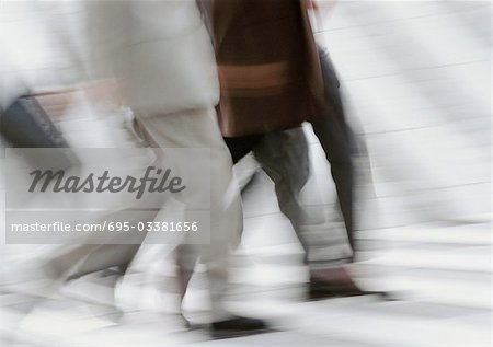 Business people walking on pedestrian crossings, low section, blurred, b&w