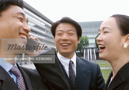 À l'aide de trois hommes d'affaires en riant, un téléphone cellulaire