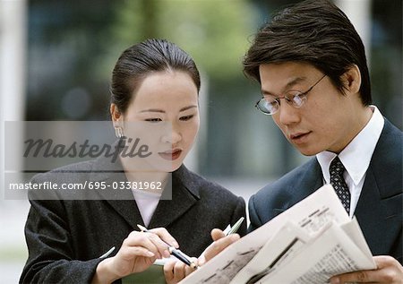 Geschäftsmann, Geschäftsfrau, Blick in die Zeitung zusammen