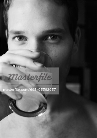 Man drinking and looking at camera, close-up, b&w