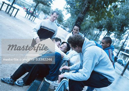 Group of young people gathered around park bench