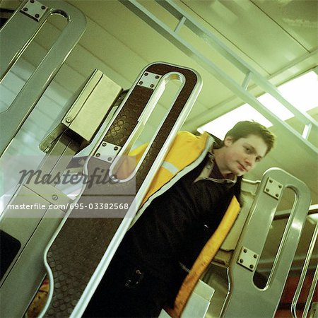 Jeune homme marchant dans porte tourniquet en métro.