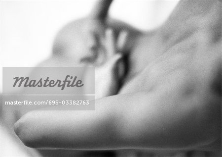 Woman lying on stomach, hands crossed behind back, close-up, black and white.