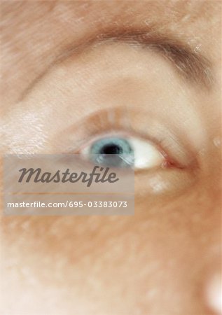 Woman's blue eye and raised eyebrow, close up, blurred.