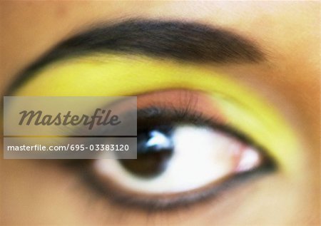 Oeil de femme avec ombre à paupières jaune et orange, très gros plan