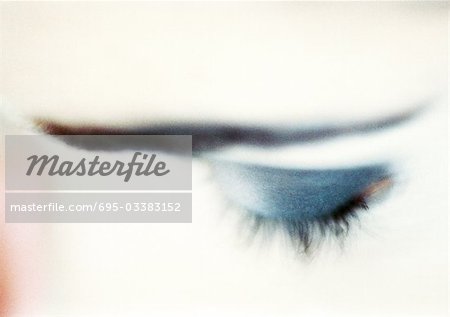 Woman's closed eye with blue eye shadow, close-up, high angle view, blurry.