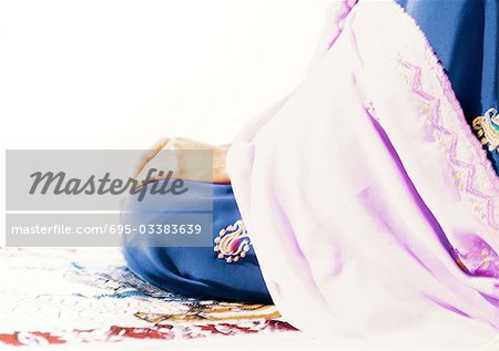 Muslimische Frau sitzt auf einem Gebetsteppich