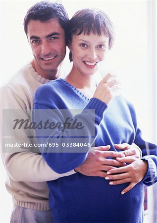 Man with arms around pregnant woman, portrait
