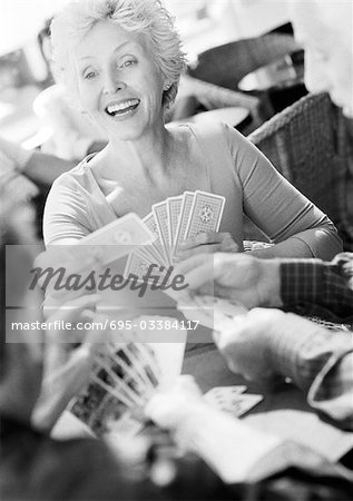 Mature woman playing cards, blurred foreground, B&W