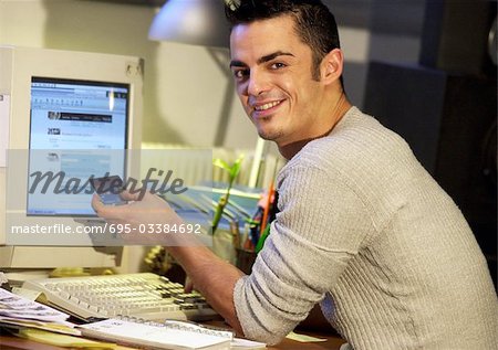 Man sitting at computer, holding credit card, portrait