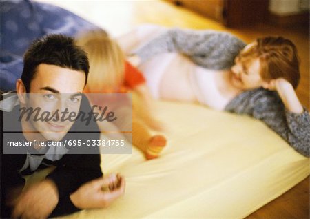 Couple and child lying on bed