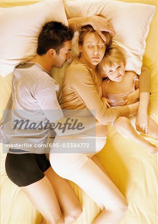 Mann, eine schwangere Frau und Kind liegen im Bett, erhöhte Ansicht