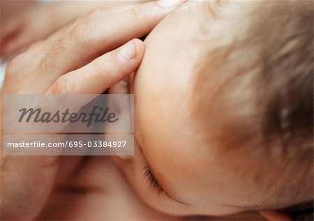 Adult's hand on baby's face, close-up