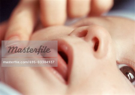 Adult touching baby's face, close-up