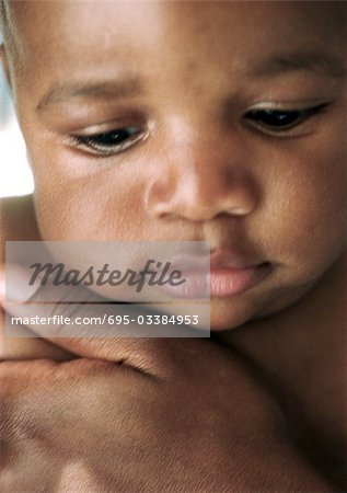 Baby with adult's hand on chest, close-up