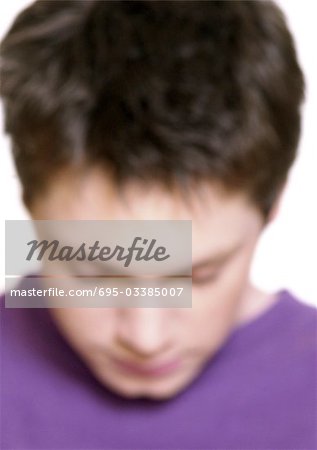 Teenage boy bending head forward, close-up, blurred