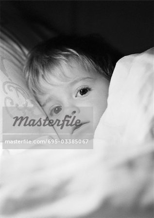 Little girl in bed under blanket, close-up, b&w