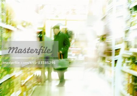 Man standing in aisle in supermarket, blurred