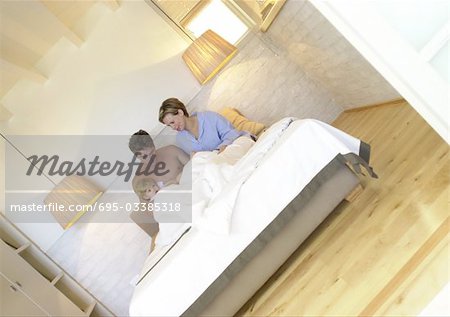 Couple assis dans son lit avec bébé