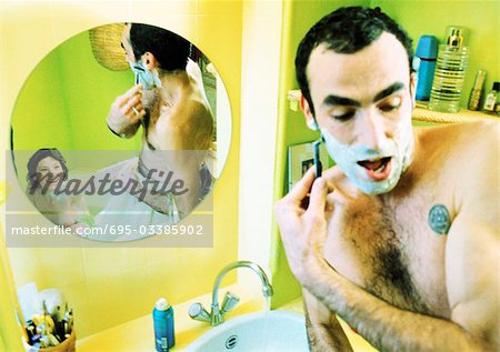 Homme à barbe devant le miroir, femme de réflexion assis dans la baignoire