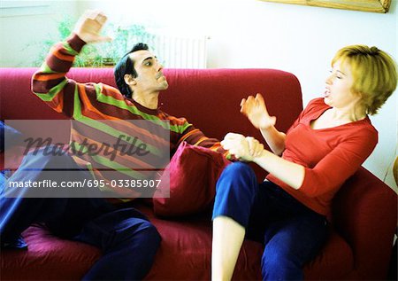 Couple sur la lutte contre le canapé, main de l'homme soulevées, femme broncher.