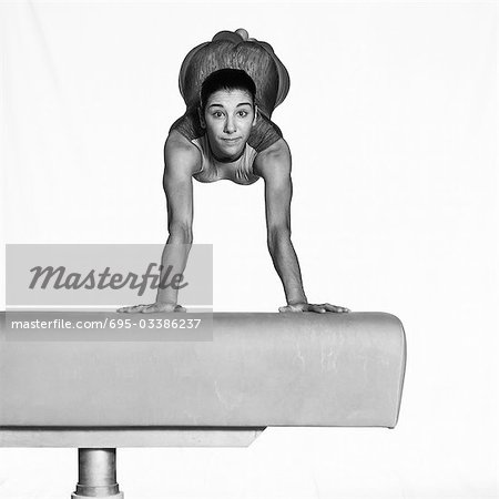 Young woman balancing on beam, looking at camera
