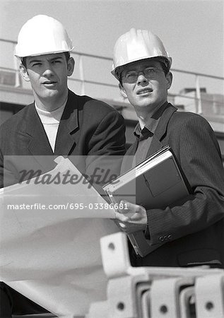 Two men with hard hats holding blueprints, b&w