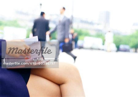 Businesswoman holding agenda on lap, close-up