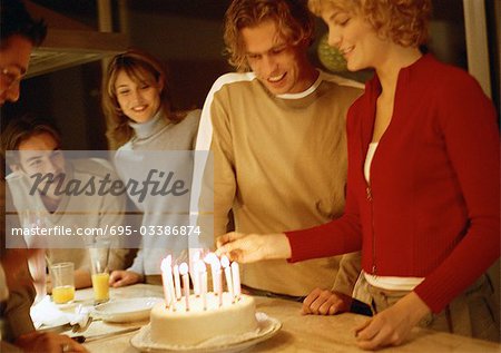 Woman lighting birthday candles in group