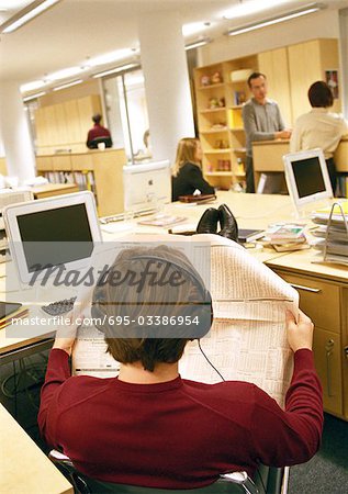 Businessman looking at paper in office, rear view.