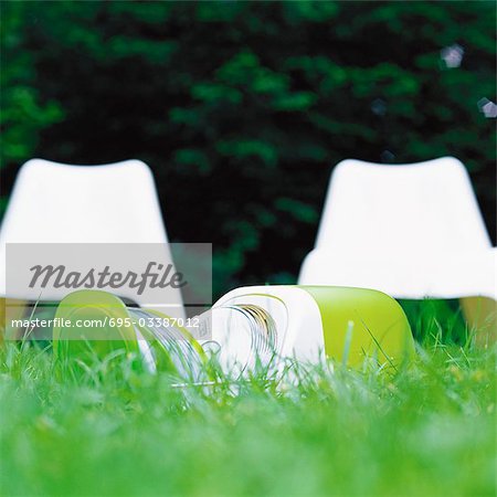 CD case, open on grass, white plastic chairs in background