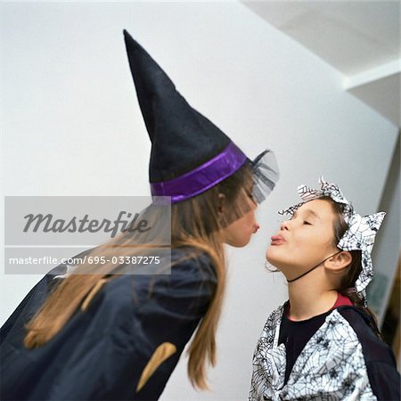 Two girls wearing costumes, sticking out tongues at each other