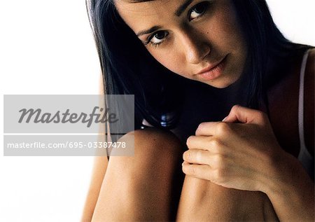 Woman hugging knees, looking at camera, close up