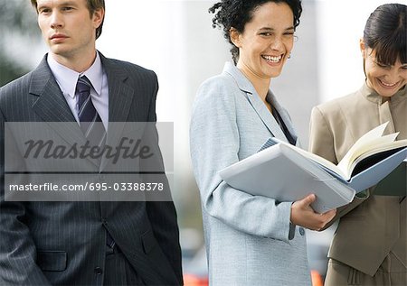 Businesswoman laughing, businessman walking by