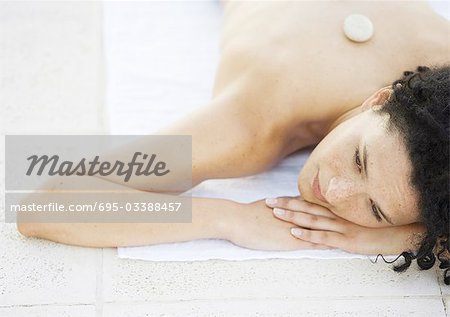 Woman lying on ground, receiving lastone therapy