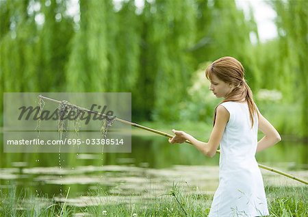 Mädchen mit Stock mit Algen hängen von diesem Teich im Hintergrund