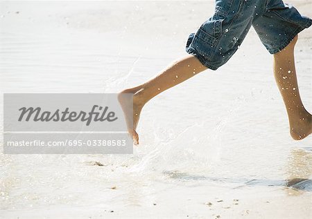 Kind läuft in der Brandung am Strand