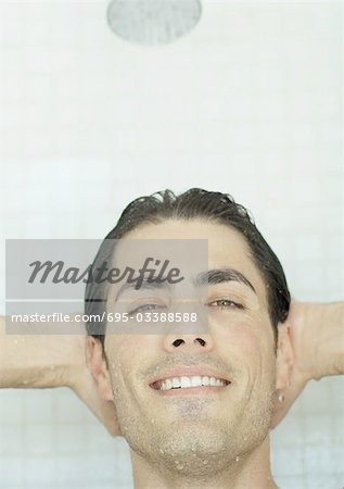 Man smiling with hands behind head in shower